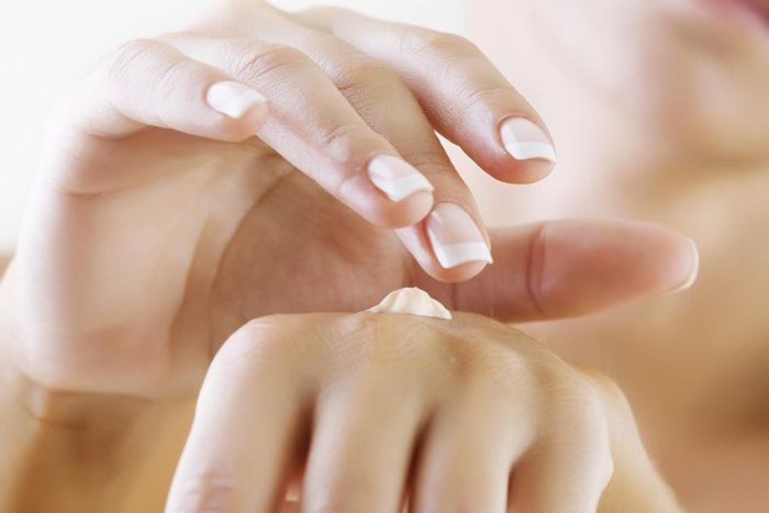 closeup of female hands applying hand cream